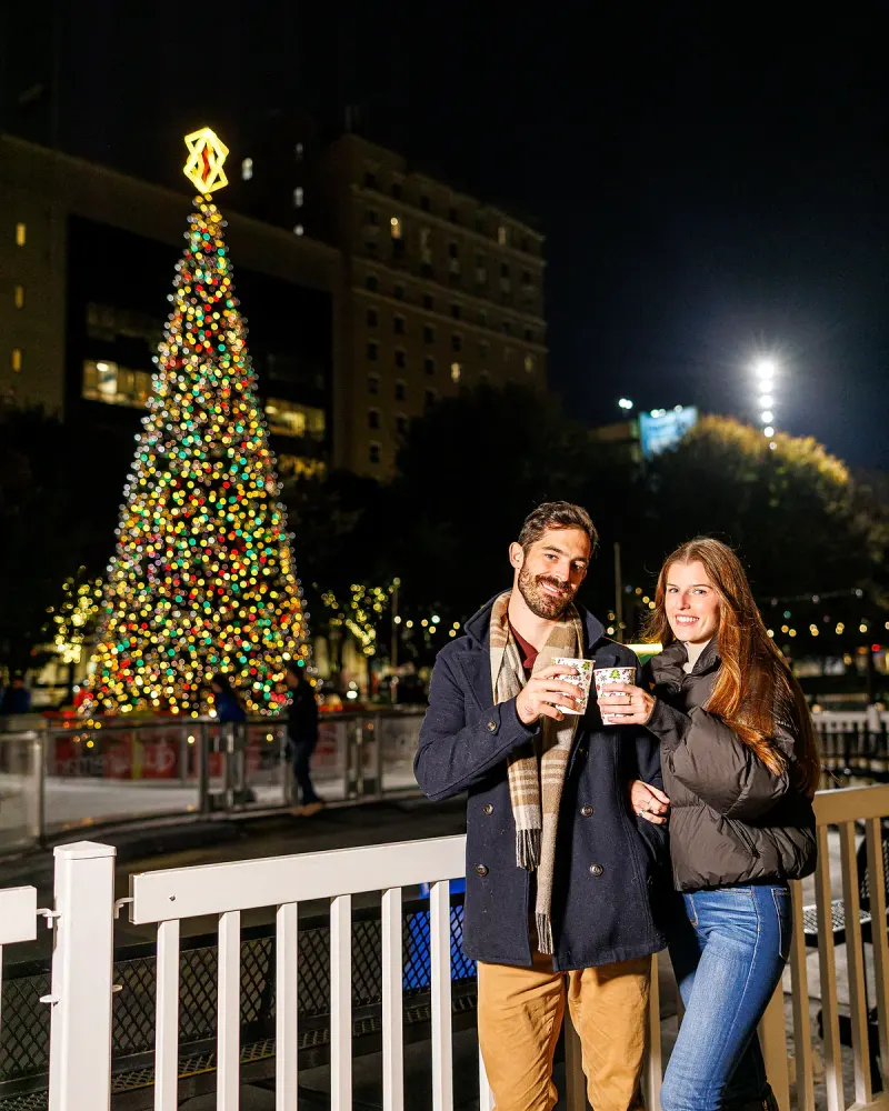 A couple enjoying warm drinks beside the illuminated rink