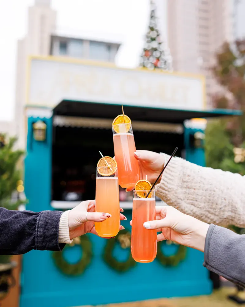 Friends raising festive drinks beside the City Rink cafe